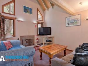 a living room with a couch and a table and a tv at Granite Peaks 1 in Thredbo