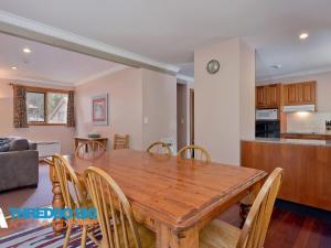 a dining room and kitchen with a wooden table and chairs at Granite Peaks 1 in Thredbo