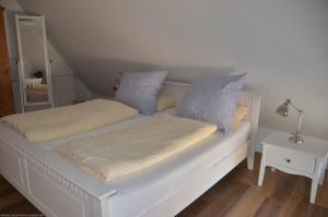 a bed with white sheets and blue pillows on it at Emes Stuuv in Oevenum