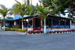 a building with palm trees and flowers in a parking lot at Hotel Las Palmeras Gachancipa in Gachancipá