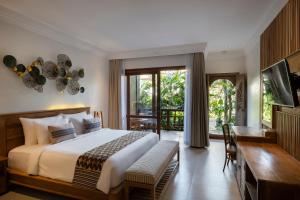 a bedroom with a large bed and a desk and a window at Vije Boutique Resort & Spa in Ubud