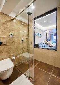 a bathroom with a toilet and a glass shower at Sea Queen Beach Resort & Spa in Colva
