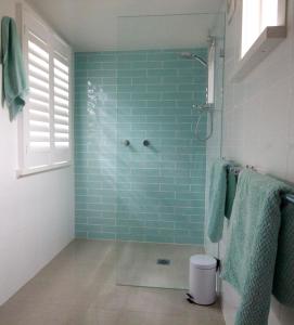 y baño con ducha de azulejos azules. en Boatsheds, en Sawtell