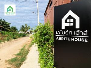 un letrero para una casa de apartamentos al lado de un camino de tierra en Tiny house on Koh Lanta only 2 mins walk to the beach en Ban Mo Nae