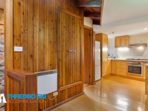 a kitchen with wood paneled walls and a refrigerator at Wombiana in Thredbo