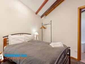 une chambre avec un lit dans une pièce blanche dans l'établissement Wombiana, à Thredbo