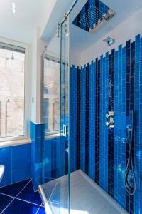 a blue tiled bathroom with a glass shower at La Suite Del Cavaliere in Amalfi