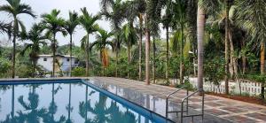 una piscina con palmeras en el fondo en Pinto's Farm Stay, en Mūlki