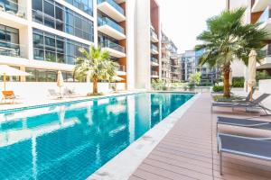 a swimming pool in a building with chairs and palm trees at 2BR With Direct Pool Access City Walk B9 in Dubai