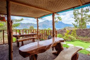 un banc en bois installé au-dessus d'une terrasse couverte dans l'établissement Break Villa Kintamani by ecommerceloka, à Kintamani