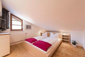 a bedroom with a large white bed with red sheets at Fewo Nachbaur Typ B in Oberjoch