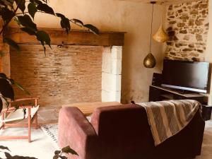 uma sala de estar com um sofá e uma televisão em Jolie maison en Périgord Vert em Nantheuil