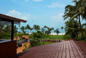 a brick walkway leading to a beach with palm trees at Sea Queen Beach Resort & Spa in Colva