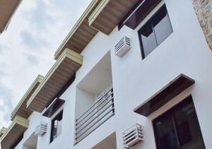 a white building with windows and wooden accents at RedDoorz Hostel @ St. Paul Village LapuLapu in Mactan