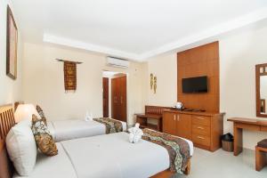 a hotel room with two beds and a desk at Sri Phala Resort & Villa in Sanur