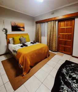 een slaapkamer met een groot bed en een gele deken bij Woodii Guest House in Sabie