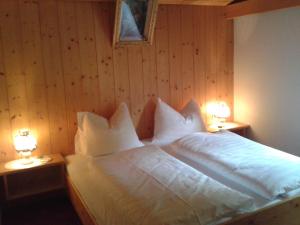 a bedroom with a bed with white sheets and two lamps at Gasthof Ochsalm in Kirchberg in Tirol