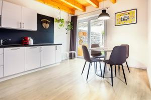 a kitchen with white cabinets and a table and chairs at Apartmány LAMA in Nižné Malatíny