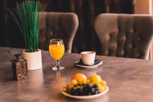 a table with a glass of orange juice and a plate of fruit at Plaza Hotel Plovdiv in Plovdiv