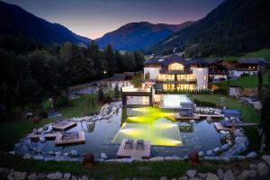 an aerial view of a house with a lake in front at FONTIS luxury spa lodge in Santa Maddalena in Casies Valbassa