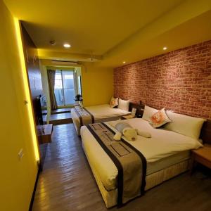a hotel room with two beds and a brick wall at Hotel Blessings in Kaohsiung