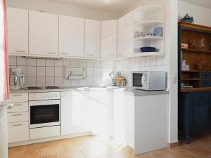 a white kitchen with white cabinets and a microwave at Kranichrast 1 Whg 4 in Zingst