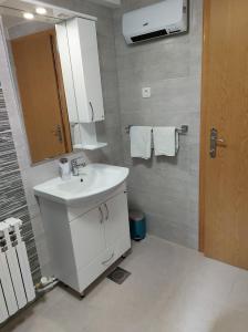 La salle de bains est pourvue d'un lavabo blanc et d'un miroir. dans l'établissement New apartment Old town with free parking, à Sarajevo
