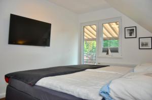 een slaapkamer met een bed en een flatscreen-tv aan de muur bij Am Alten Leuchtfeuer in Eckernförde