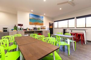 a dining room with green chairs and a wooden table at Broome Time Resort in Broome