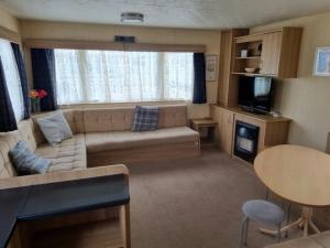 a small living room with a couch and a television at 8 BERTH CARAVAN PG30 in Chapel Saint Leonards