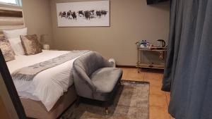 a bedroom with a bed and a chair in it at Mount Shekinah Country Hotel in Balgowan