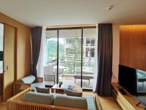 a living room with a couch and a large window at Zen Next Khao Yai By ZV in Pak Chong