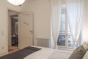a white bedroom with a bed and a balcony at Palazzo Tergesteo Tirabora Suite Apartments in Trieste