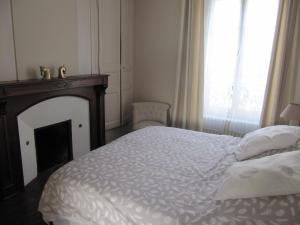 1 dormitorio con 1 cama blanca, chimenea y ventana en Suite Sainte Anne, en Beaumont-sur-Sarthe