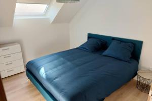 - un lit bleu avec des oreillers bleus dans une chambre dans l'établissement Gîte au cœur des Combrailles, à Saint-Georges-de-Mons