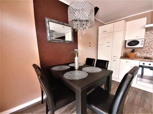 a dining room table with black chairs and a chandelier at Ferienwohnung Summer in Karlshagen
