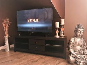 a television sitting on a entertainment center with a statue at Ferienwohnung Summer in Karlshagen +3 photos