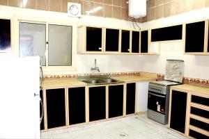 eine Küche mit schwarzen und weißen Schränken und einem Waschbecken in der Unterkunft العييرى للوحدات المفروشة تبوك6 in Tabuk