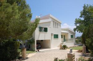 una casa blanca con un coche aparcado en la entrada en Villa Chrysanthia, en Polis Chrysochous