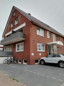 a car parked in front of a brick building at Hotel Pension Norddeich in Norddeich