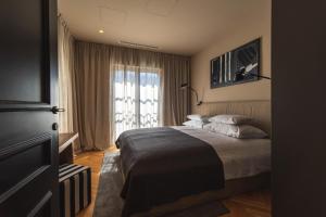 a bedroom with a bed and a large window at DESIGN hotel VERBENICUM in Vrbnik