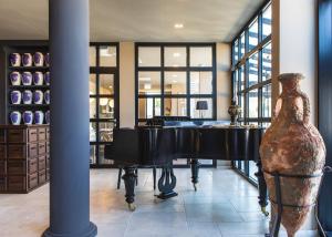 a piano and a vase in a room with windows at DESIGN hotel VERBENICUM in Vrbnik
