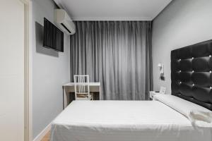 Un dormitorio con una gran cama blanca y una ventana en Hostal Los Ángeles en Madrid