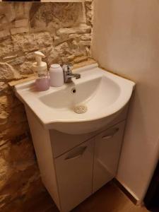 a white sink in a bathroom with a stone wall at John' s House in Omodos in Limassol