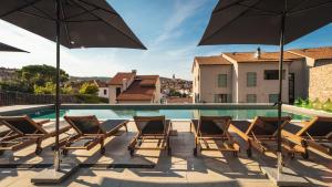 un patio con sillas y sombrillas junto a una piscina en DESIGN hotel VERBENICUM en Vrbnik