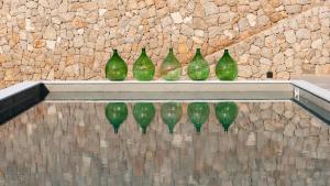 a row of green glass vases sitting on a wall at DESIGN hotel VERBENICUM in Vrbnik