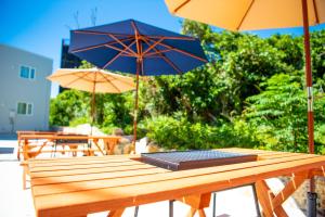- une table en bois avec 2 parasols sur la terrasse dans l'établissement Kourijima L'hotels, à Nakijin