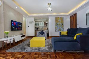 een woonkamer met een blauwe bank en een tafel bij Tranquil Residence by Edmor Suites in Nairobi