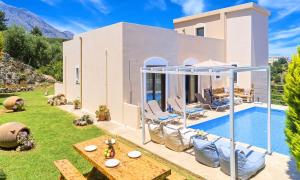 a villa with a swimming pool in front of a house at Cretan Sunny Villa Heated Pool in Kournás