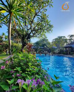 - une piscine dans un complexe avec des fleurs violettes dans l'établissement Tirta Sari Bungalow, à Pemuteran